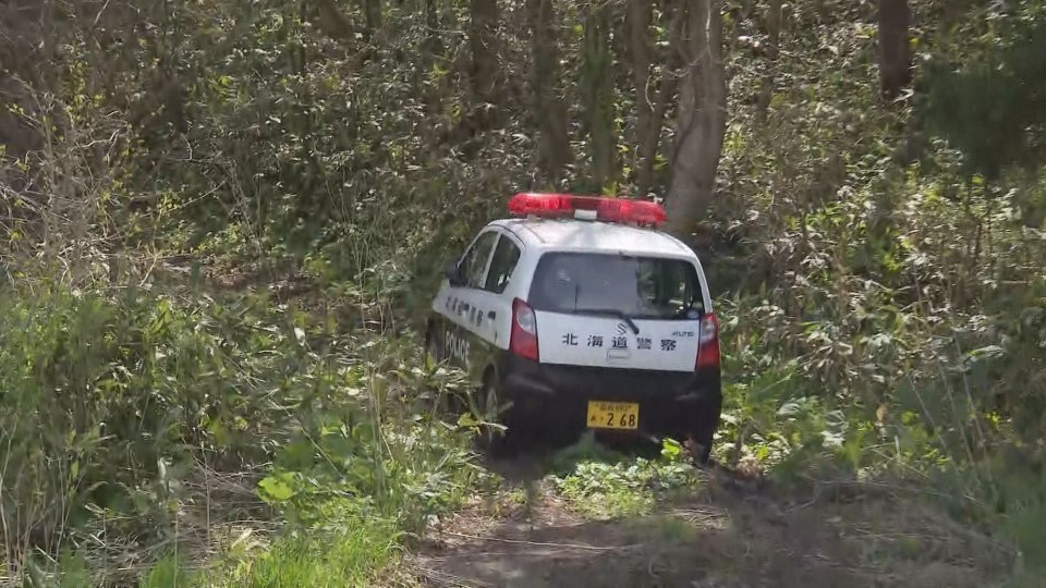 捜索のため山林に入る警察車両(北海道厚沢部町・2日)