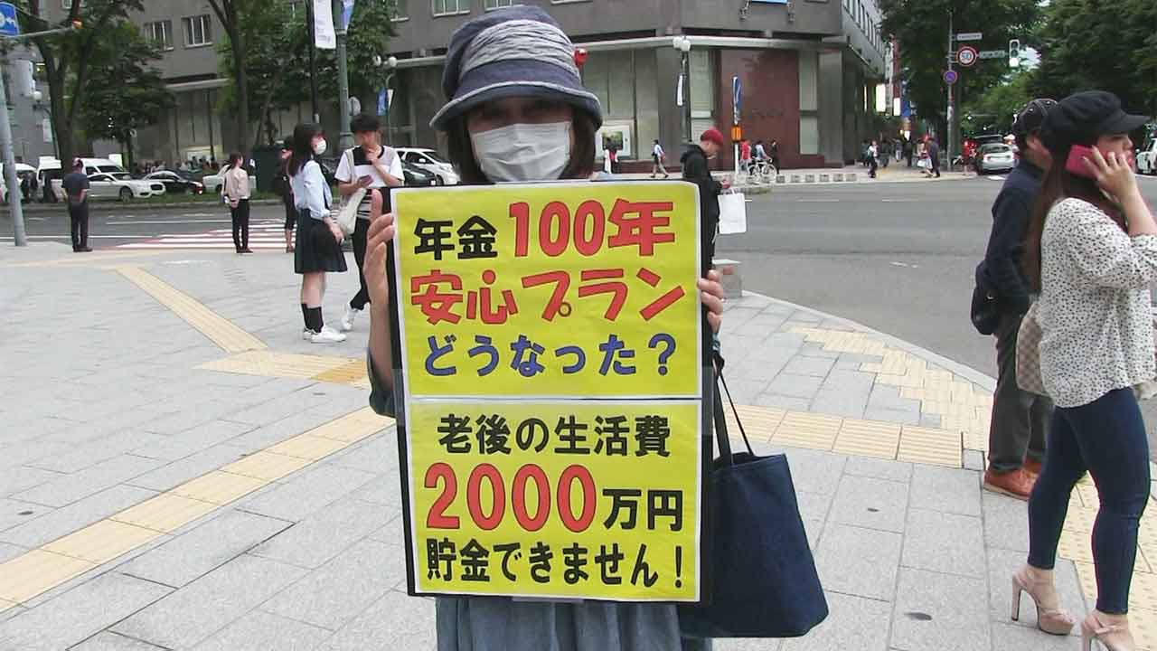 年金問題のプラカードを掲げようとして排除された女性(写真)